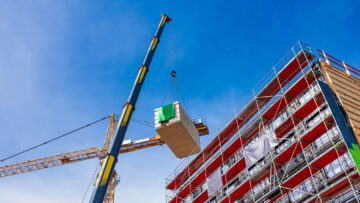 Crane lifting a wooden building module to its position in the st